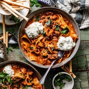slow cooker lasagna soup in a bowl topped with ricotta and fresh herbs.